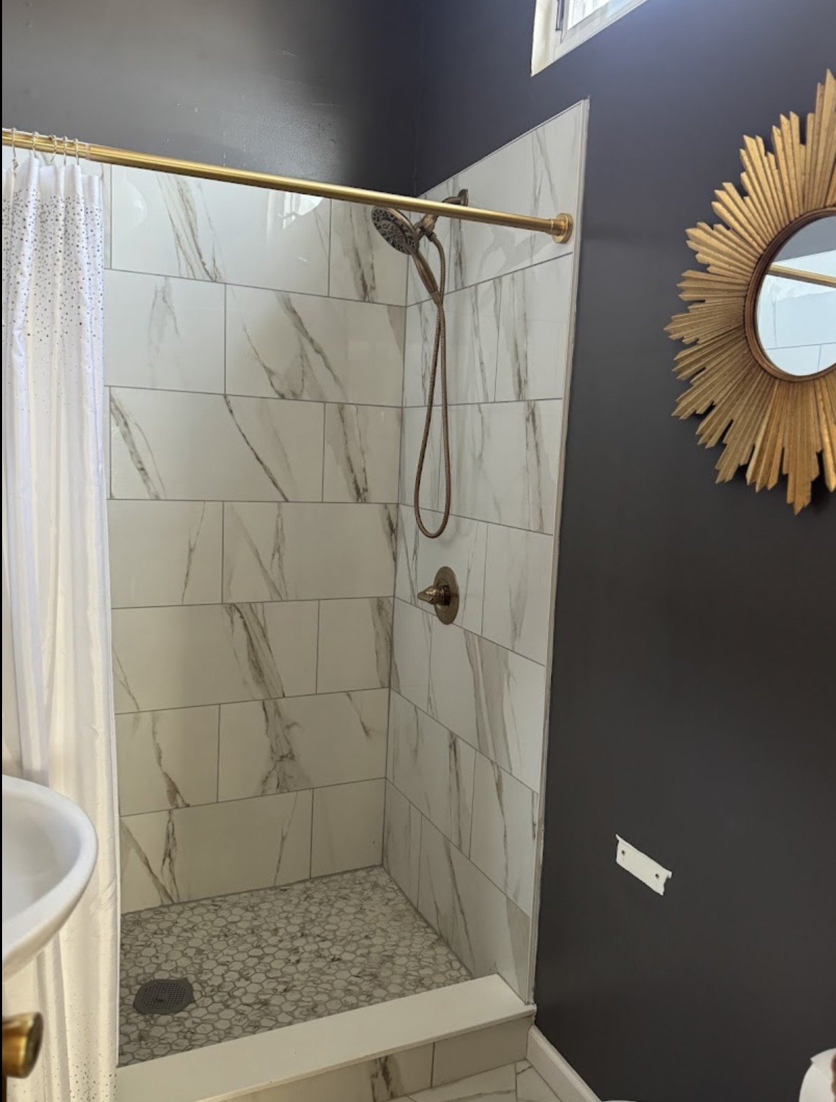 Marble shower with brushed gold fixtures and mosaic floor