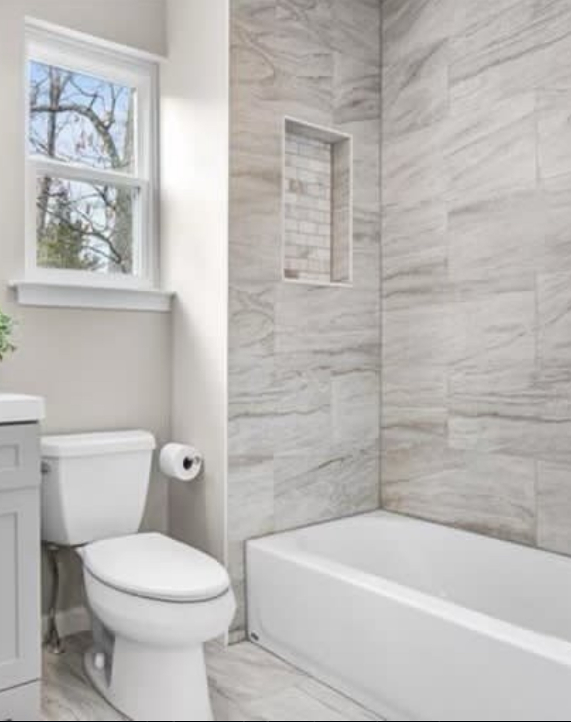 Marble-look tub surround with custom niche and stone flooring