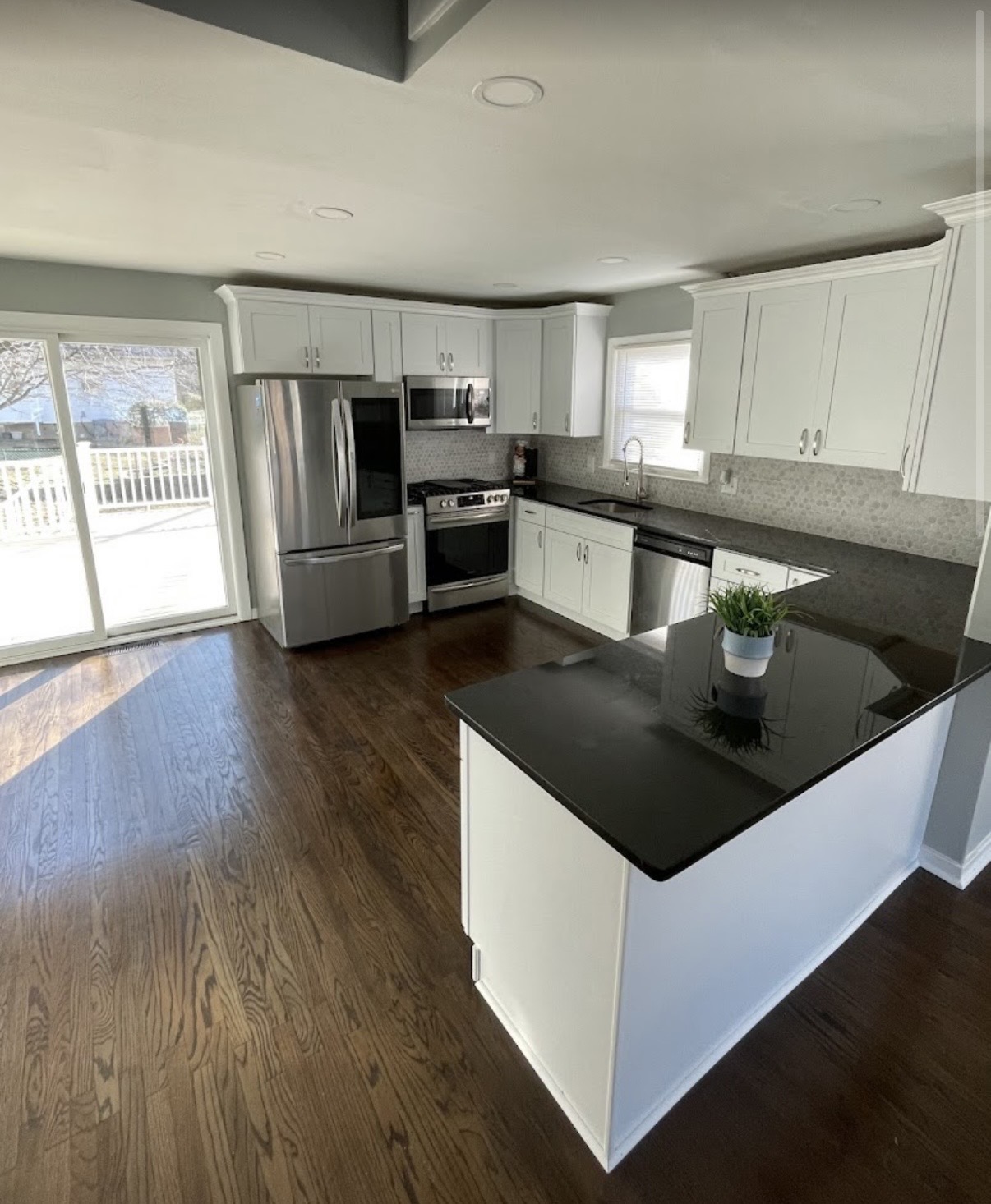 Open-concept white shaker kitchen with black quartz island